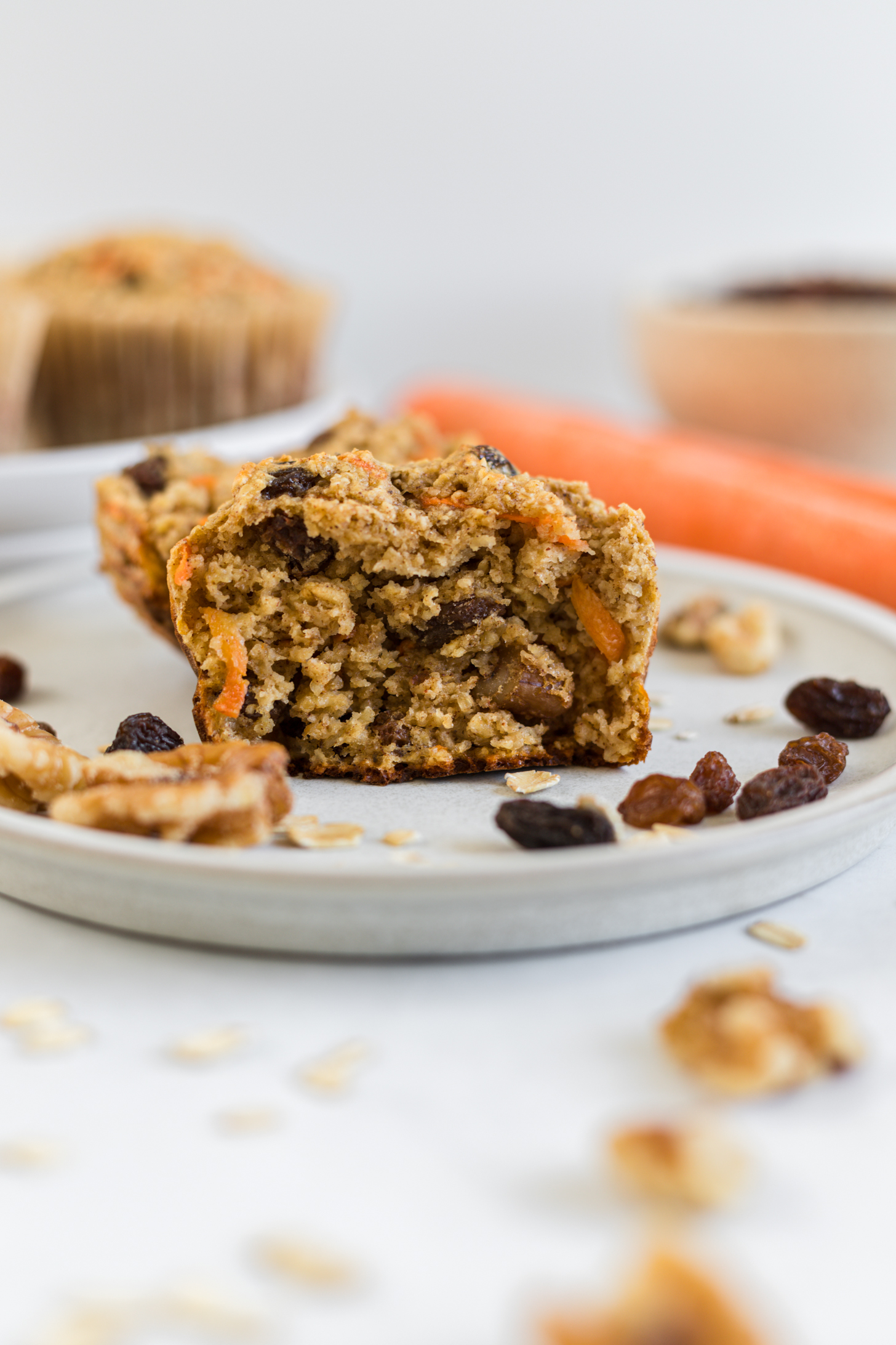 A carrot cake muffin cut in half on a plate.