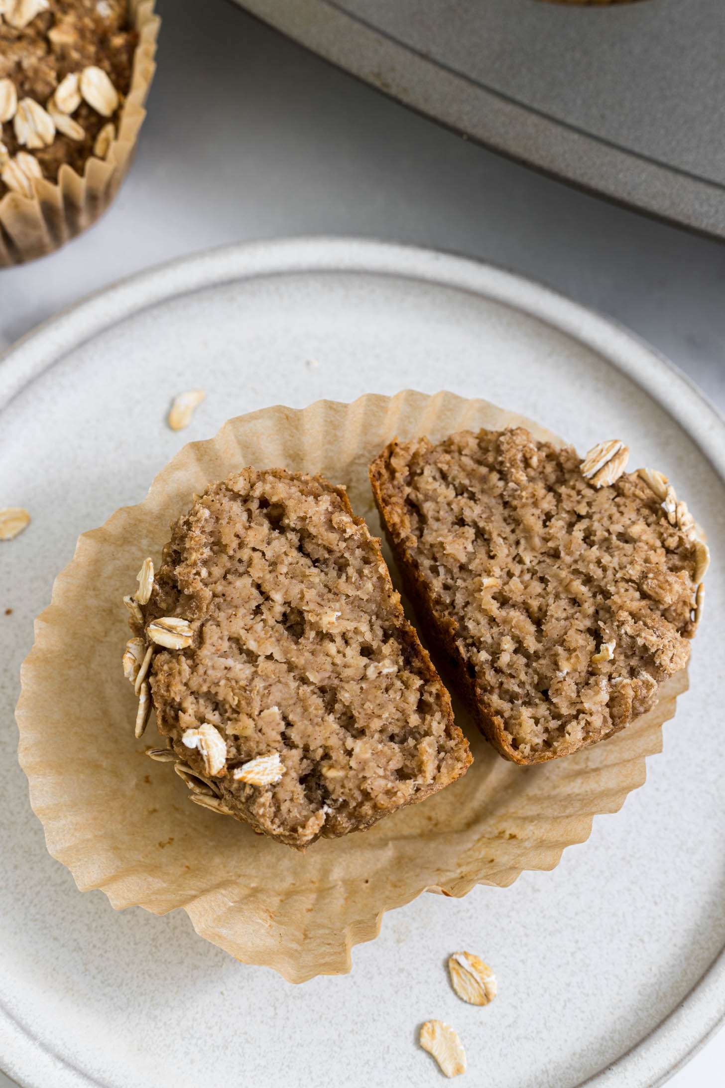 An applesauce muffin is cut in half on a plate.