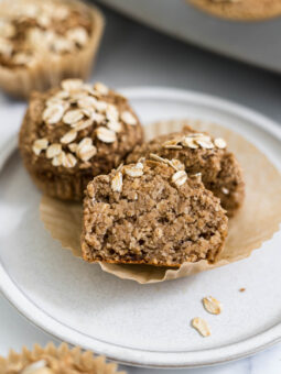 A Banana Applesauce Muffin cut in half resting on another muffin on a plate.