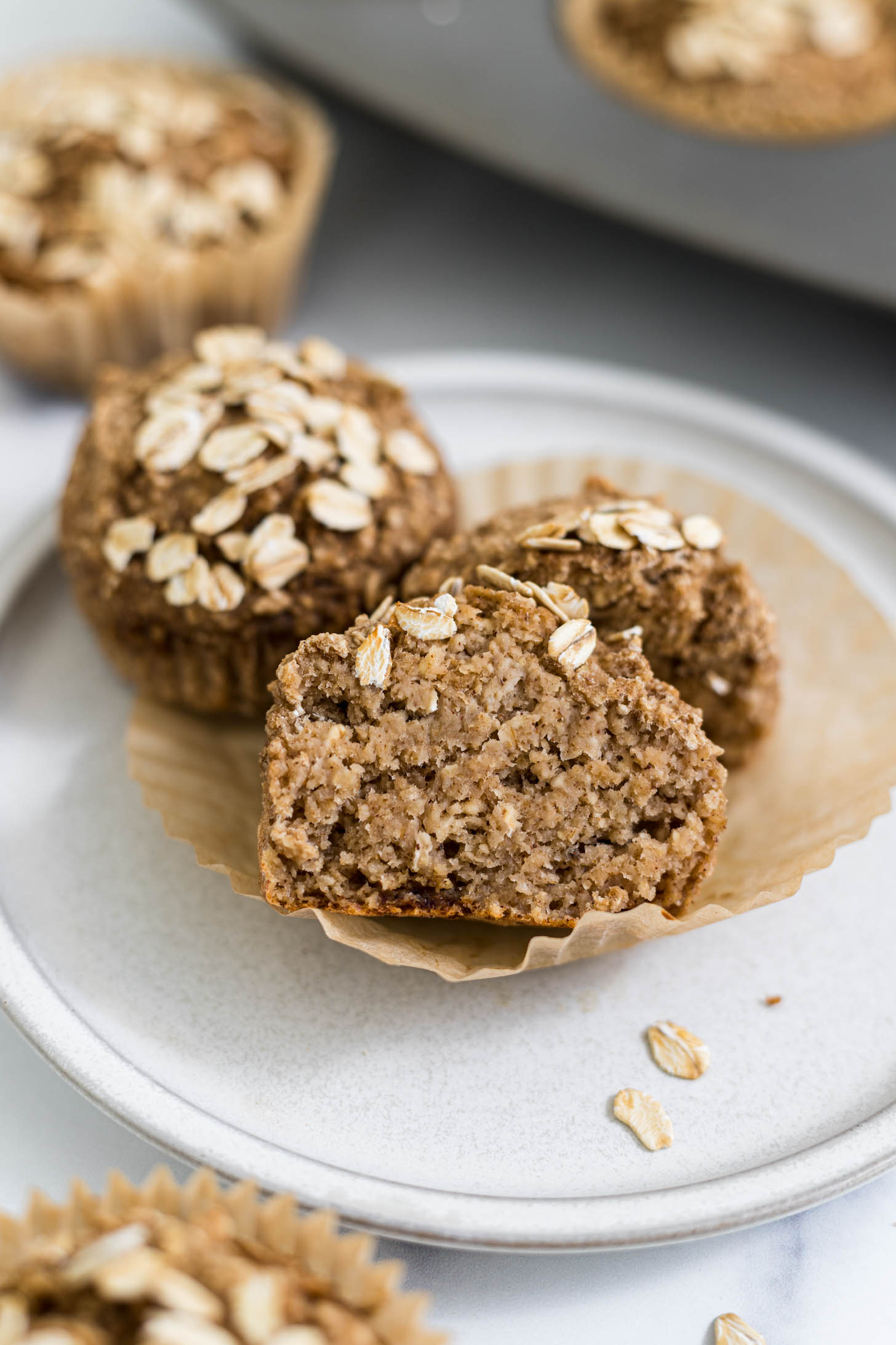 A Banana Applesauce Muffin cut in half resting on another muffin on a plate.