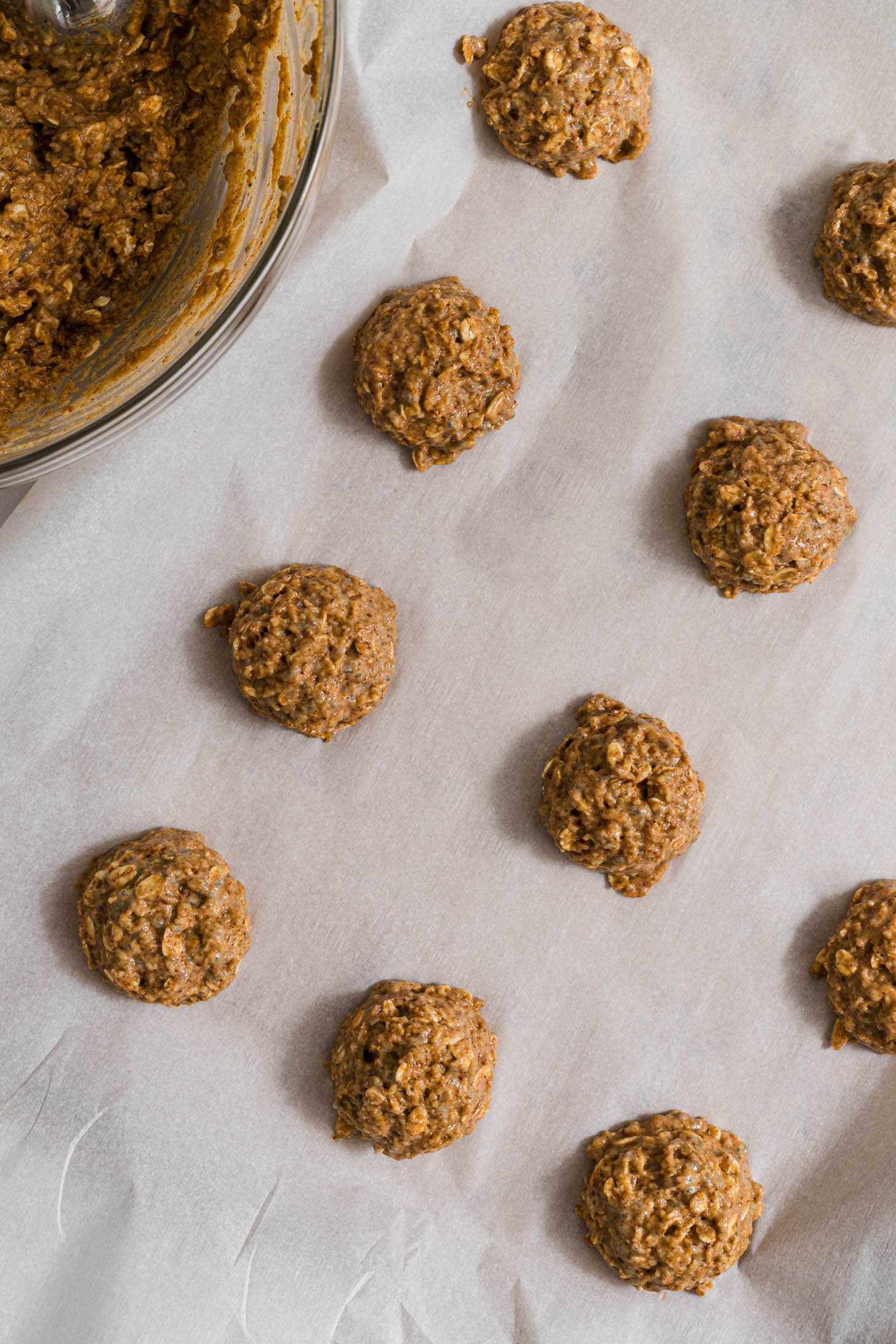 Cookie dough balls on a baking sheet with parchment paper.