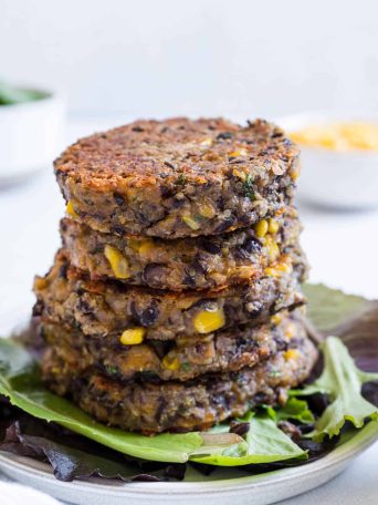 A stack of black bean fritters on a bed of lettuce.