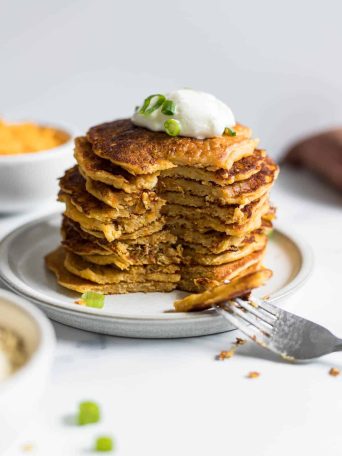 A stack of Savory Sweet Potato Pancakes with a section cut out with a fork.