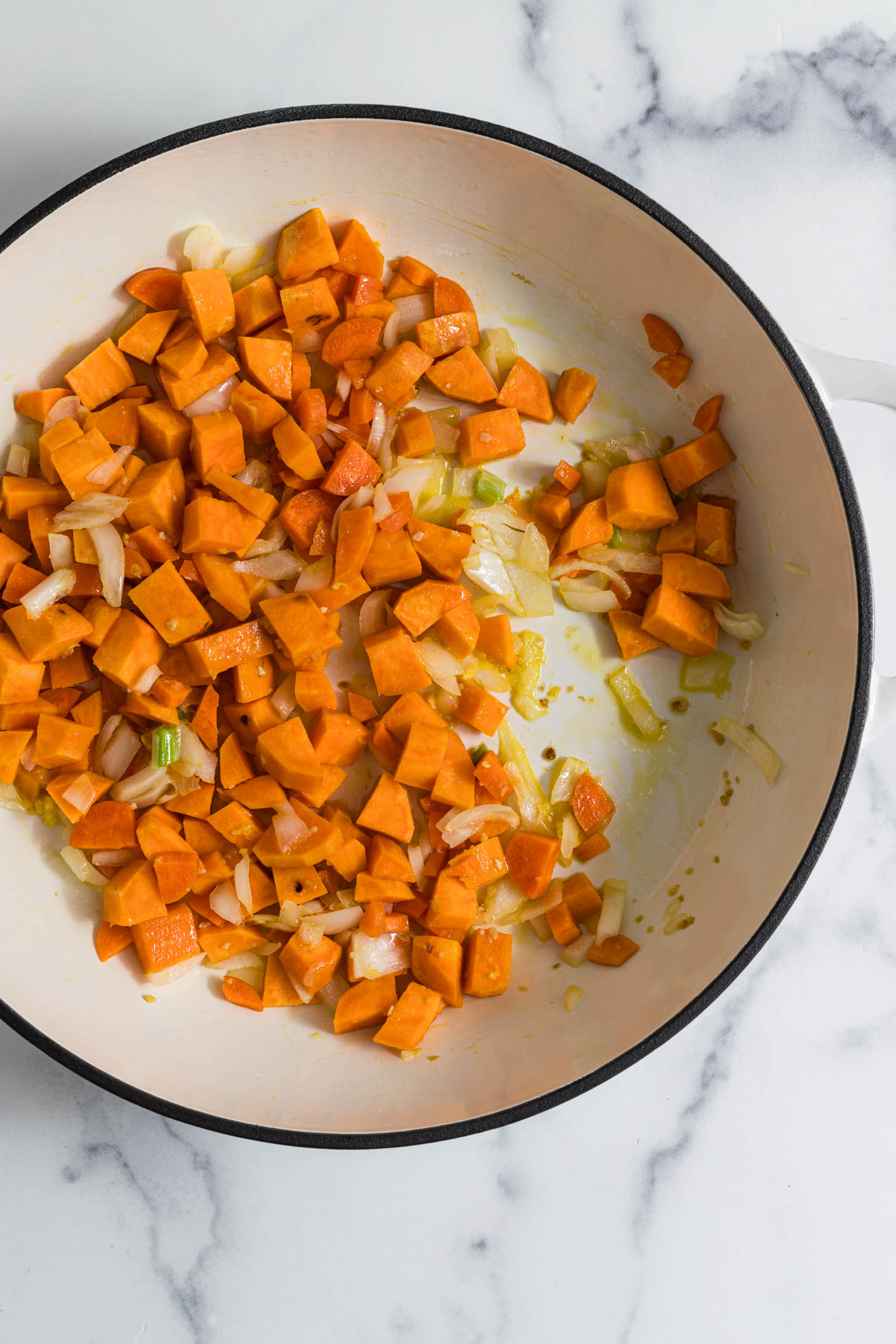 Sweet potatoes in a large pot being sauteed.