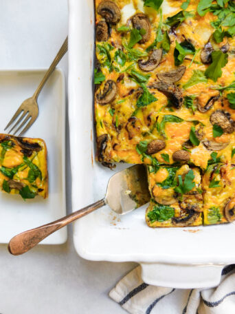 A baking dish with Potato Frittata With Caramelized Onions and a plate with a serving of the frittata.