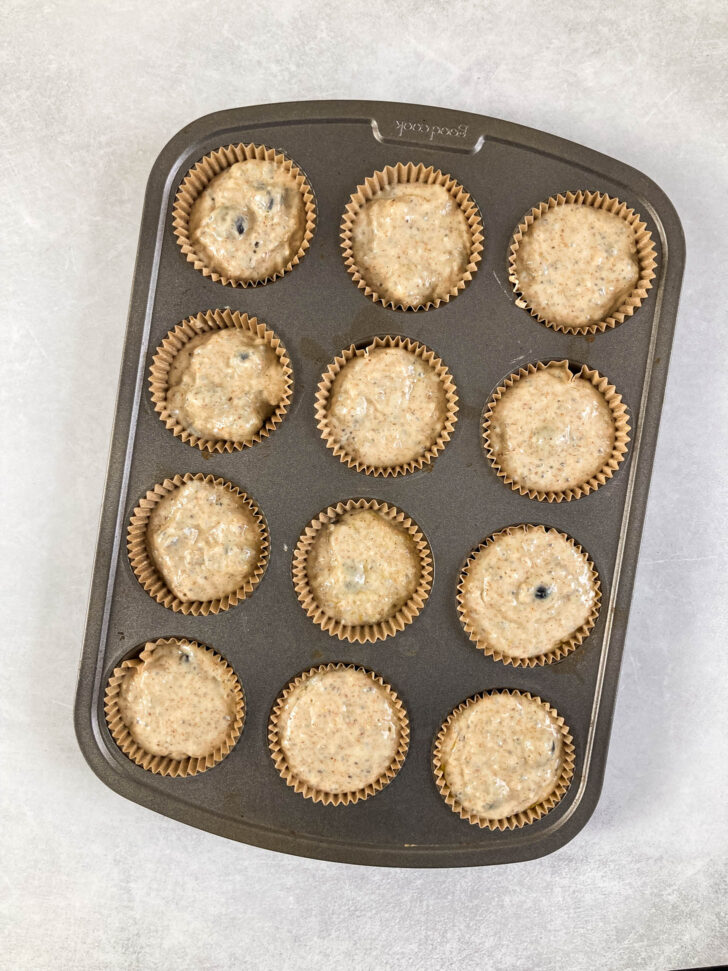 Batter in muffin liners in a muffin tray ready to be baked.