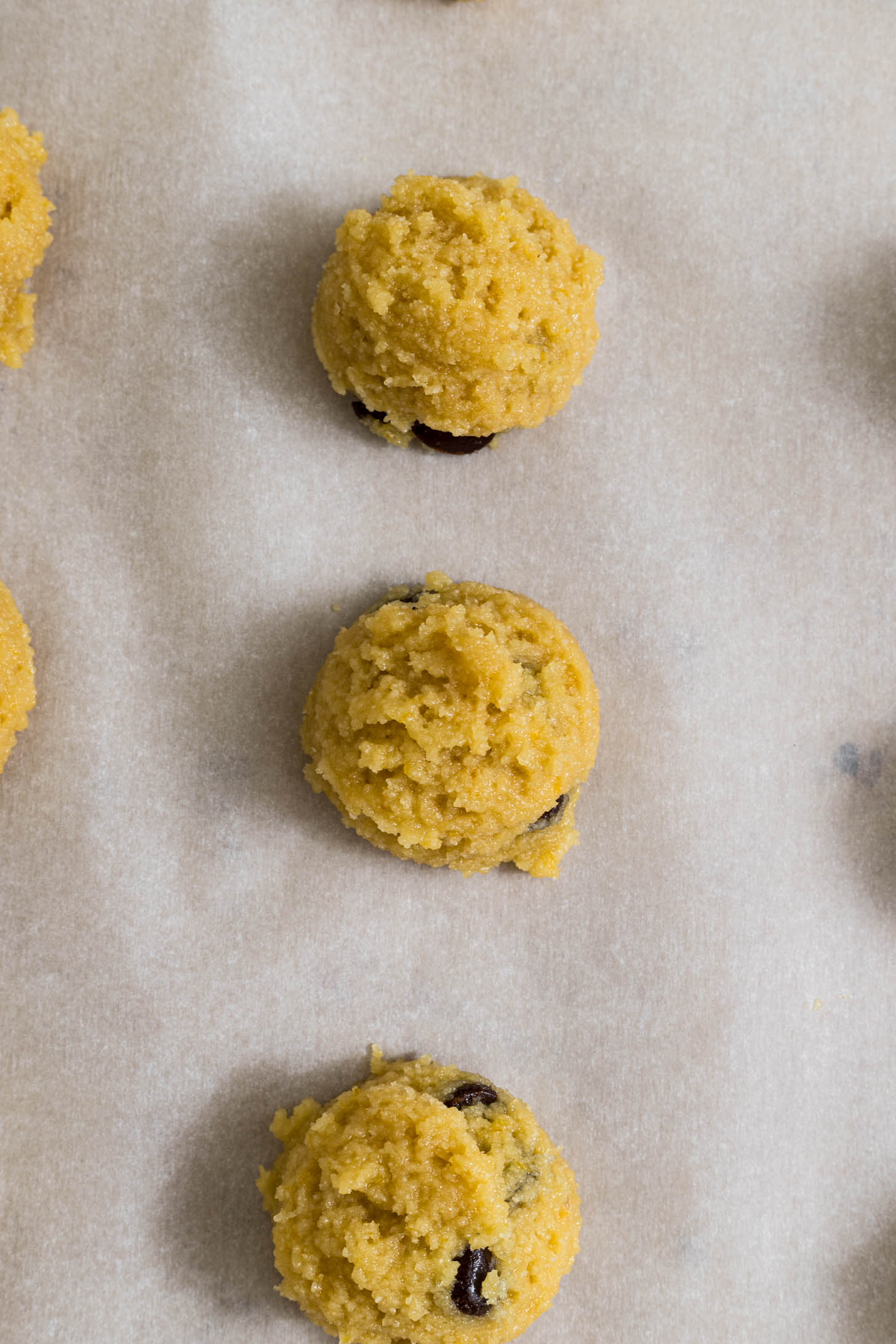 Cookie dough balls on a baking sheet with parchment paper. 