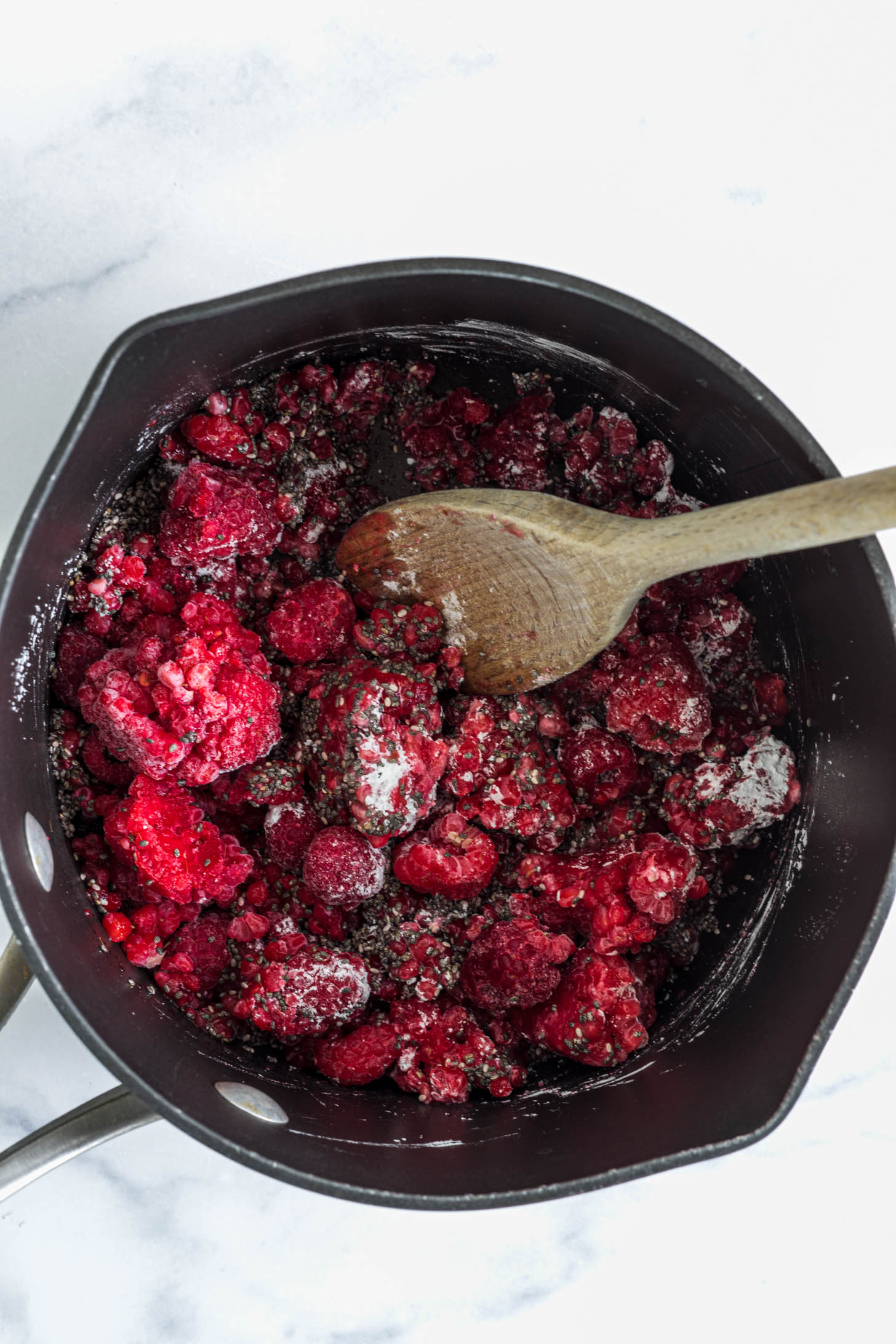 Frozen raspberries and other jam ingredients in a pot.