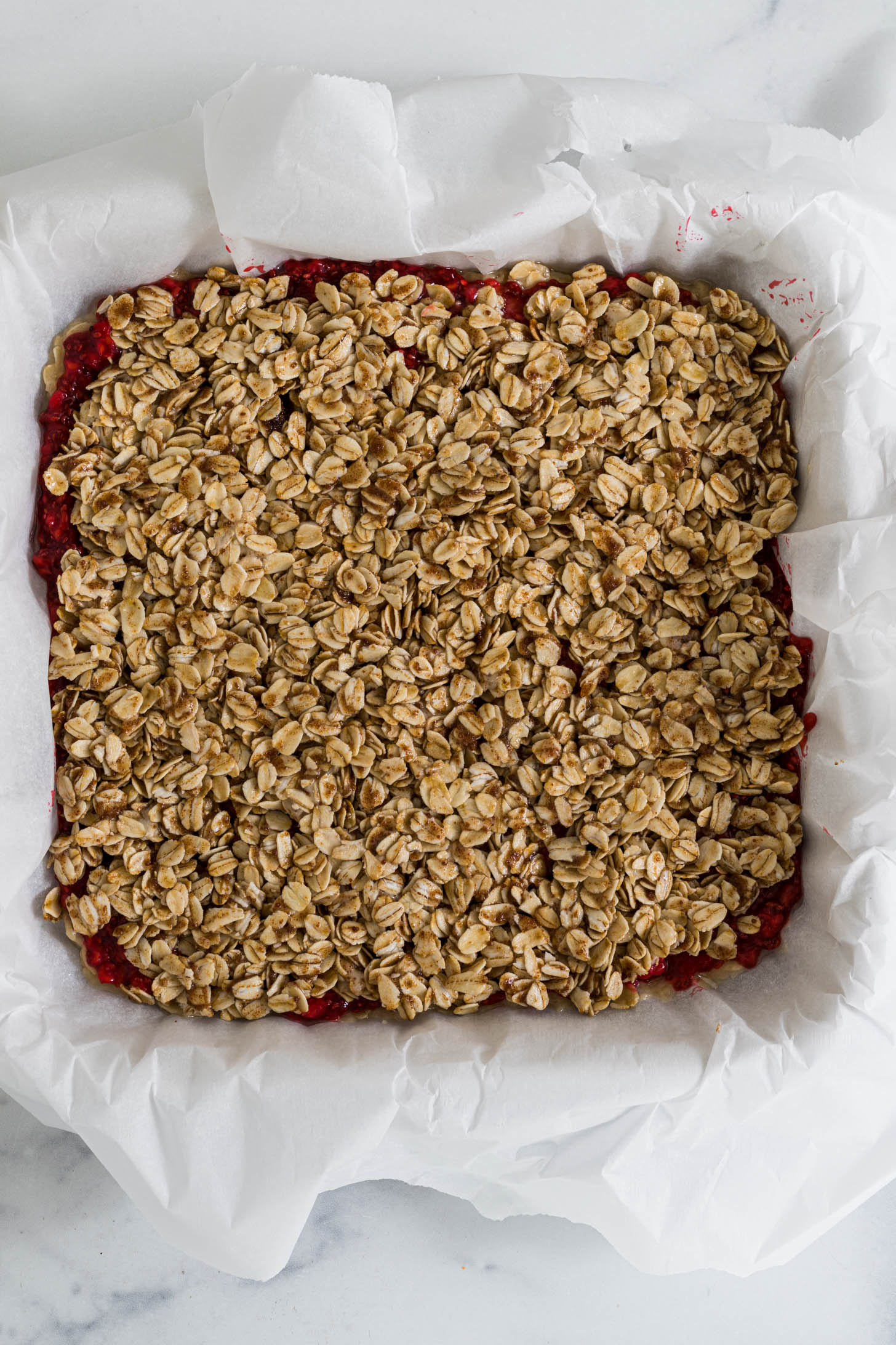 Uncooked raspberry bars with oatmeal crumble topping.