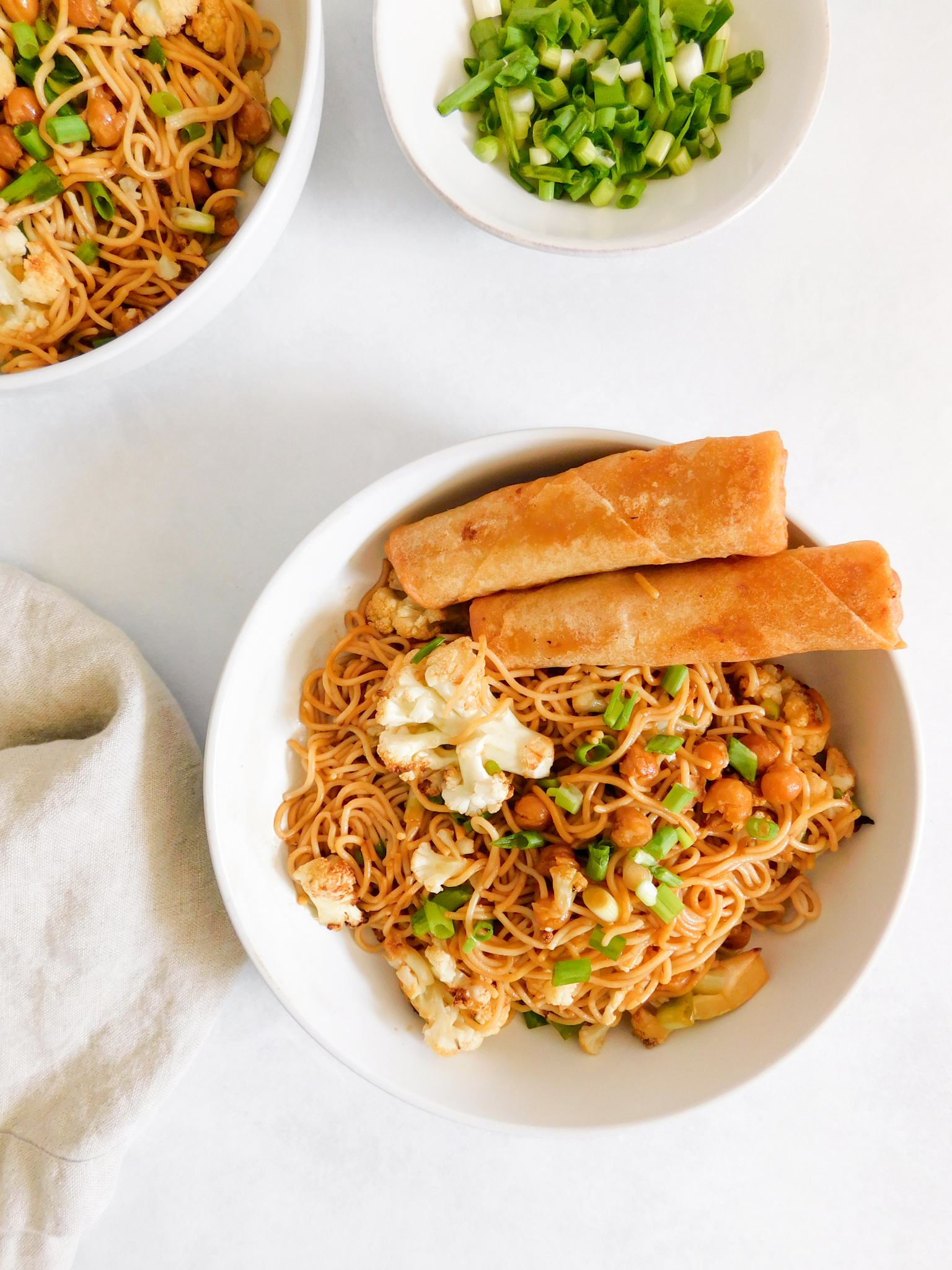 A bowl of Easy Vegan Ramen Noodles with spring rolls on the side of the bowl.