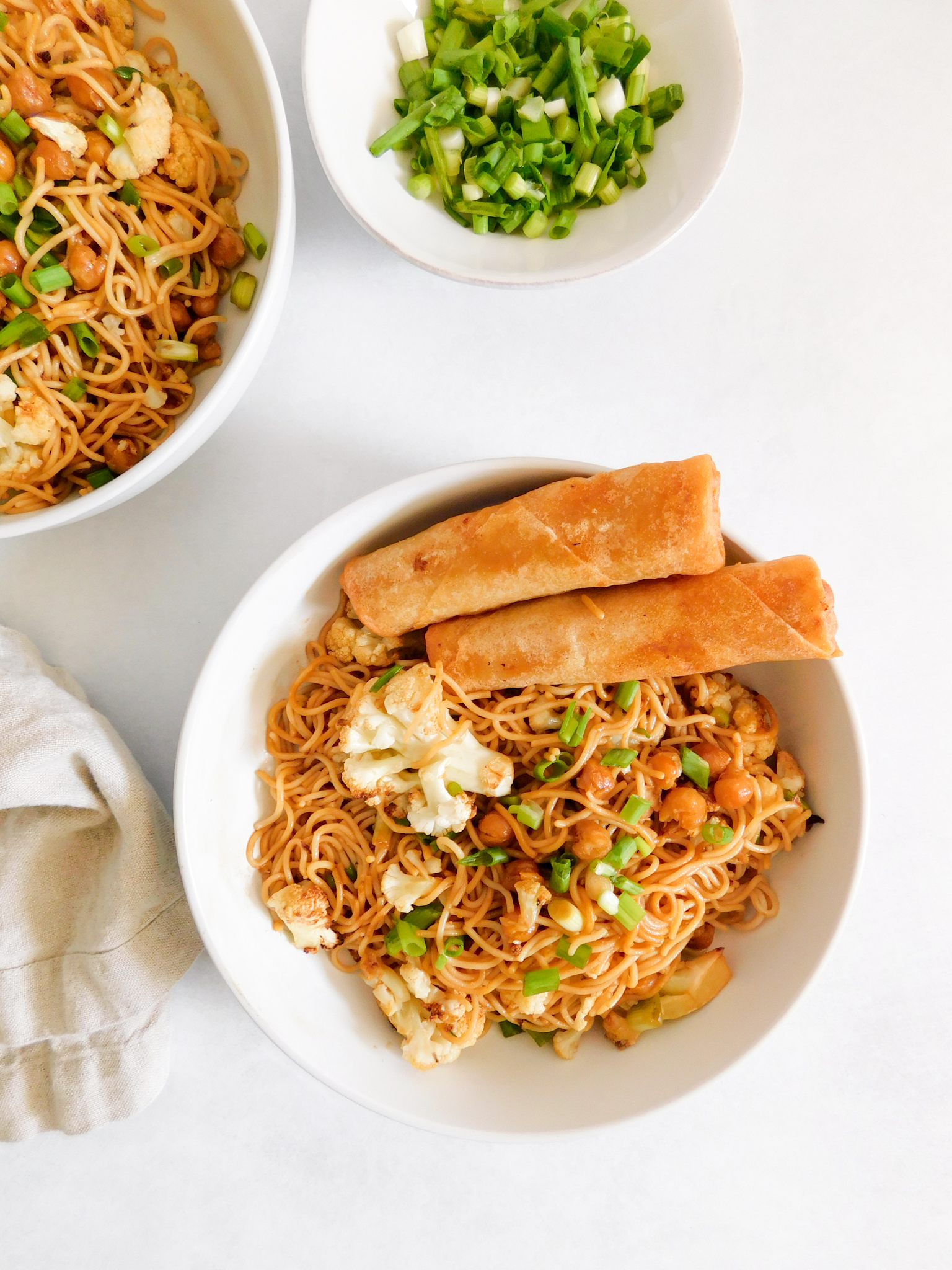 A bowl of ramen noodles with spring rolls on the side of the bowl. 