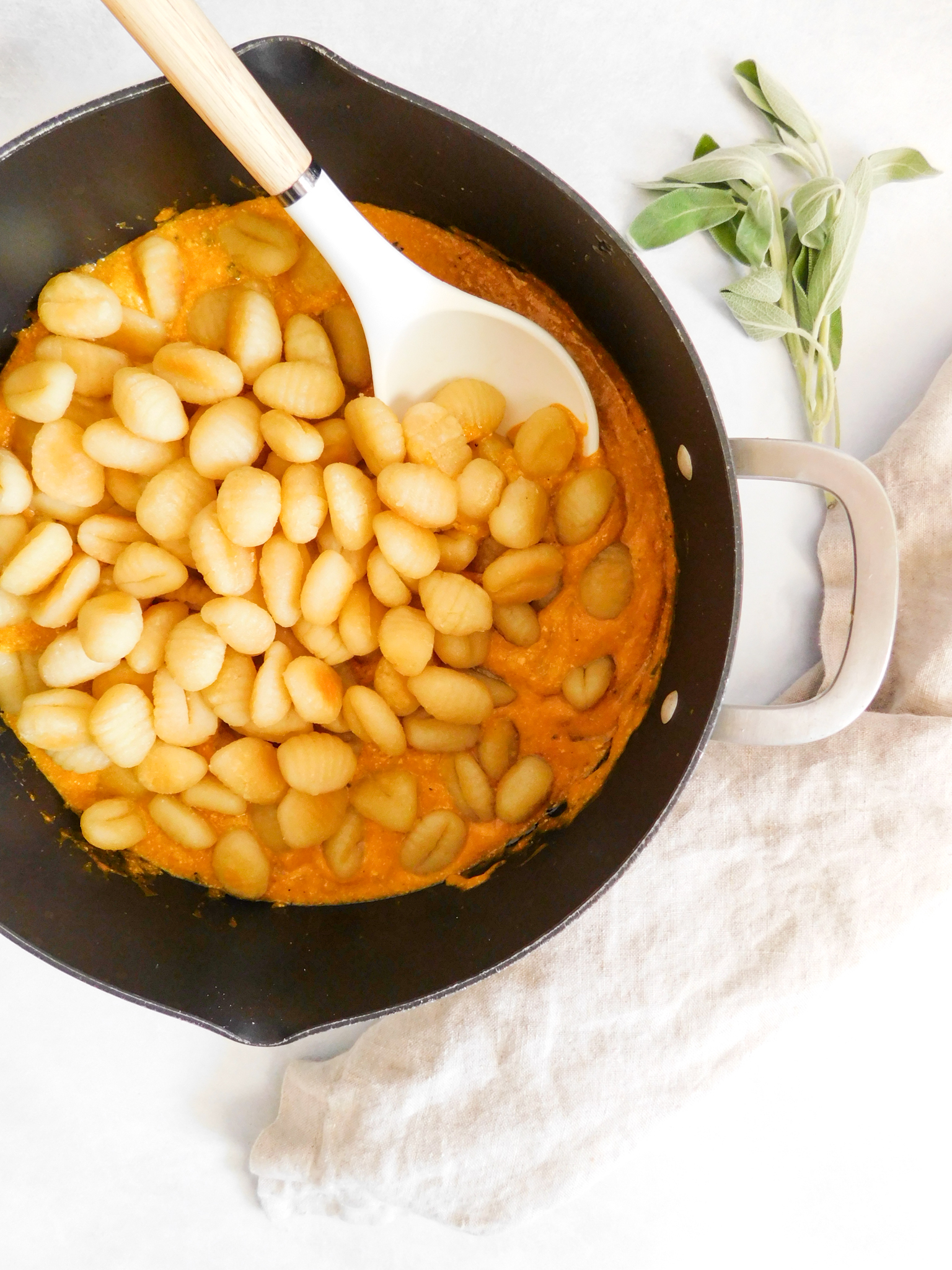 The baked gnocchi has just been added to the pumpkin pasta sauce in a large pot, but has not been stirred in yet. 