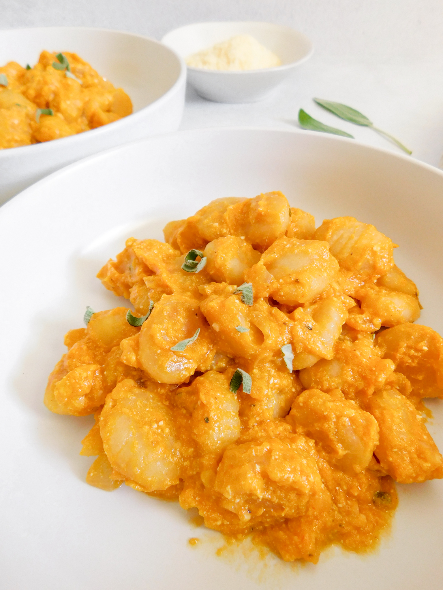 A close up shot of the Sheet-Pan Gnocchi with Pumpkin Pasta Sauce in a bowl with bits of sage sprinkled on top. 