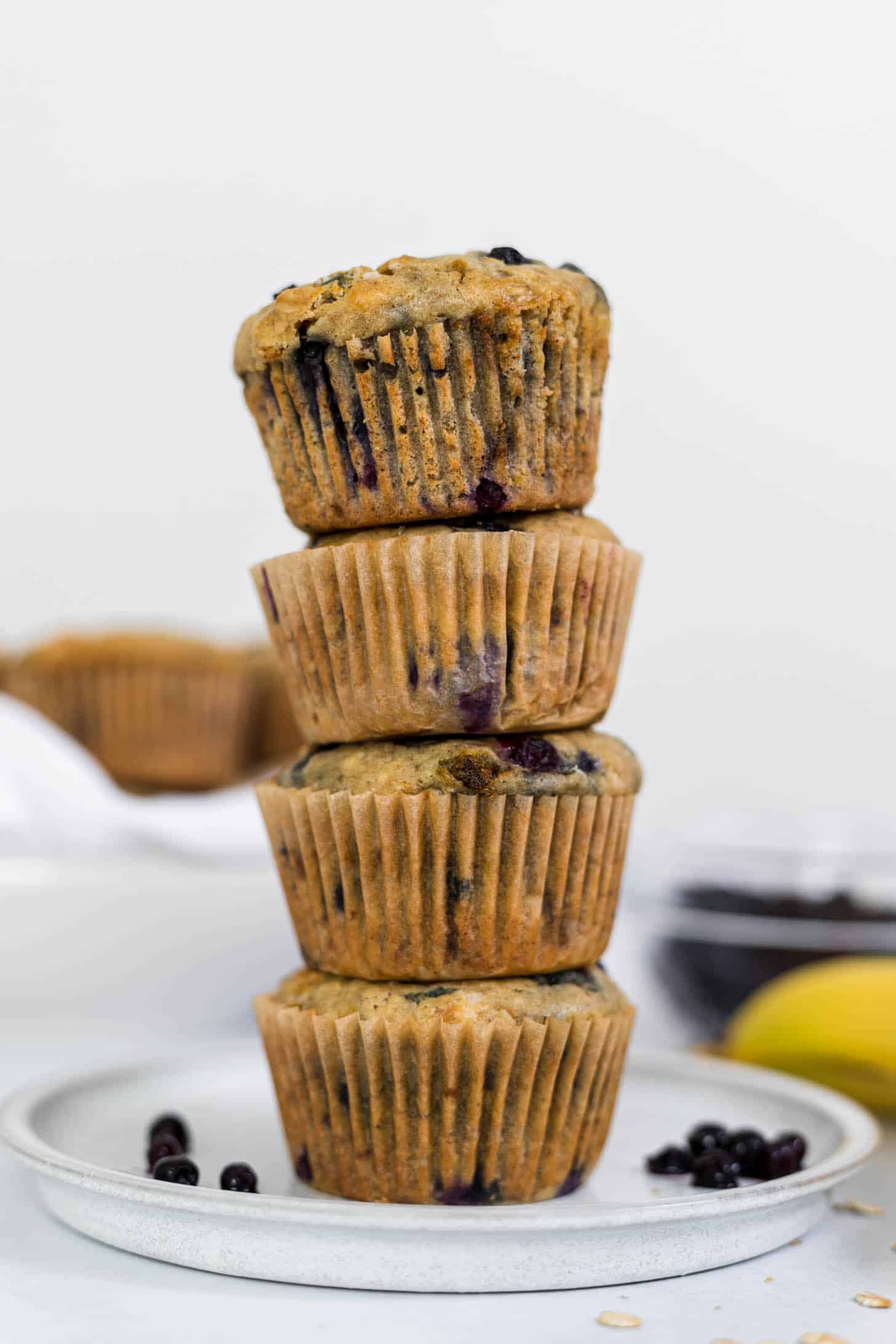 A stack of 4 Banana Blueberry Oatmeal Muffins on a plate.