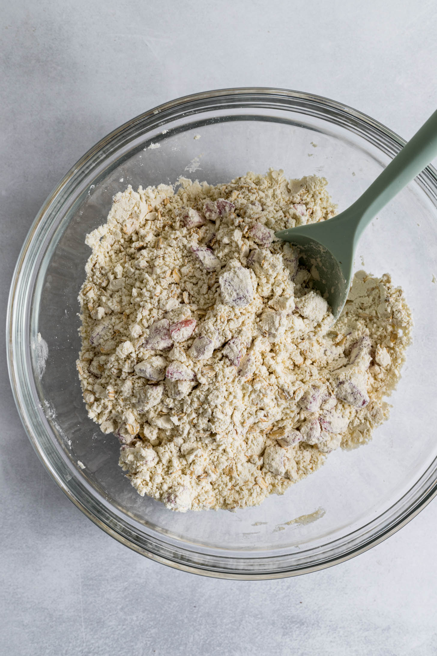 Strawberry slices mixed into dry ingredients in a bowl.