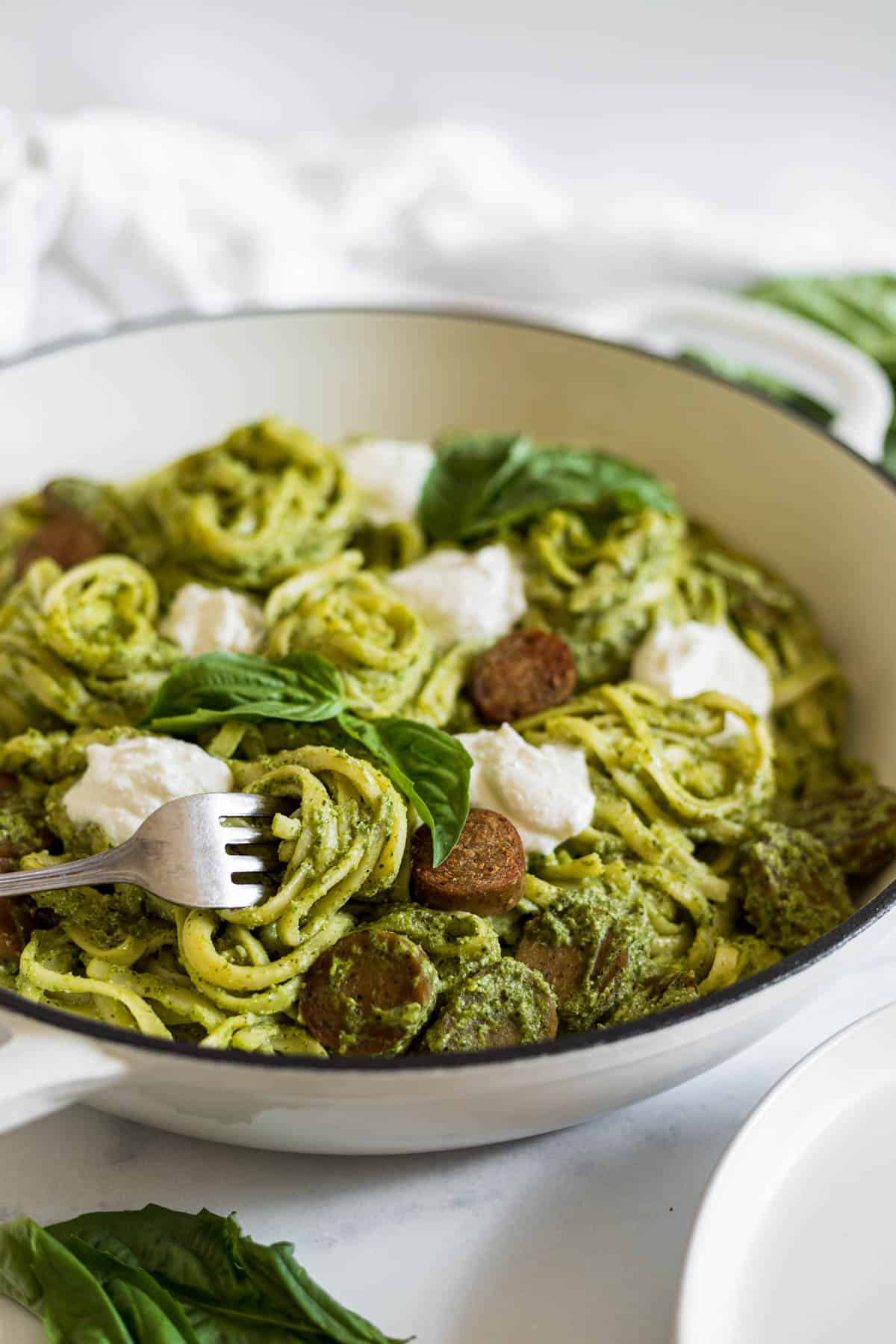 A side view of Pesto Ricotta Pasta in a braiser. A fork is turning some pasta.