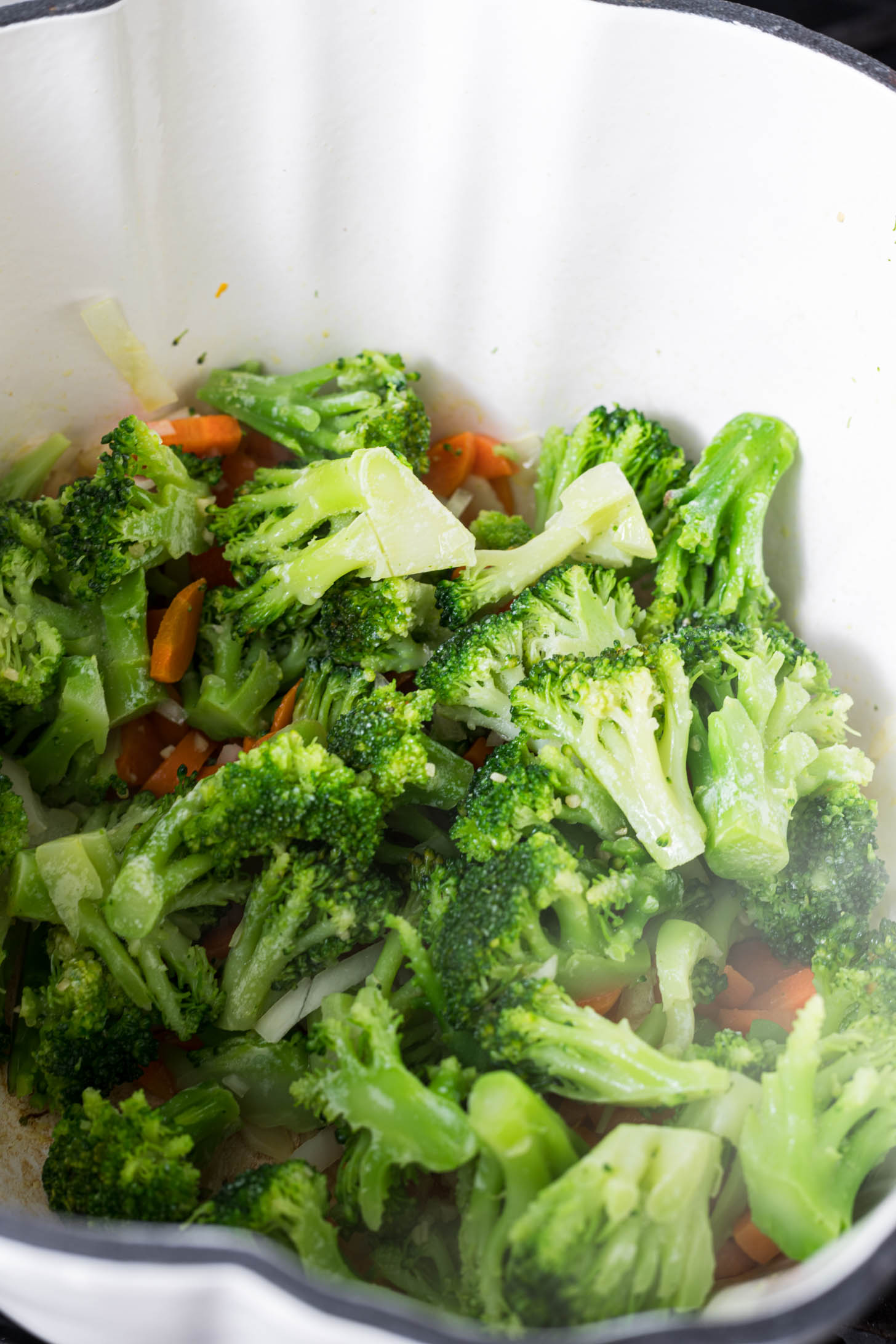 Broccoli, garlic, and onion have been added to the dutch oven.