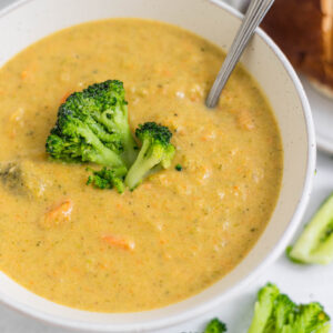 An overhead view of a bowl of gluten-free broccoli cheddar soup with a spoon in it.