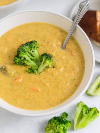 An overhead view of a bowl of gluten-free broccoli cheddar soup with a spoon in it.