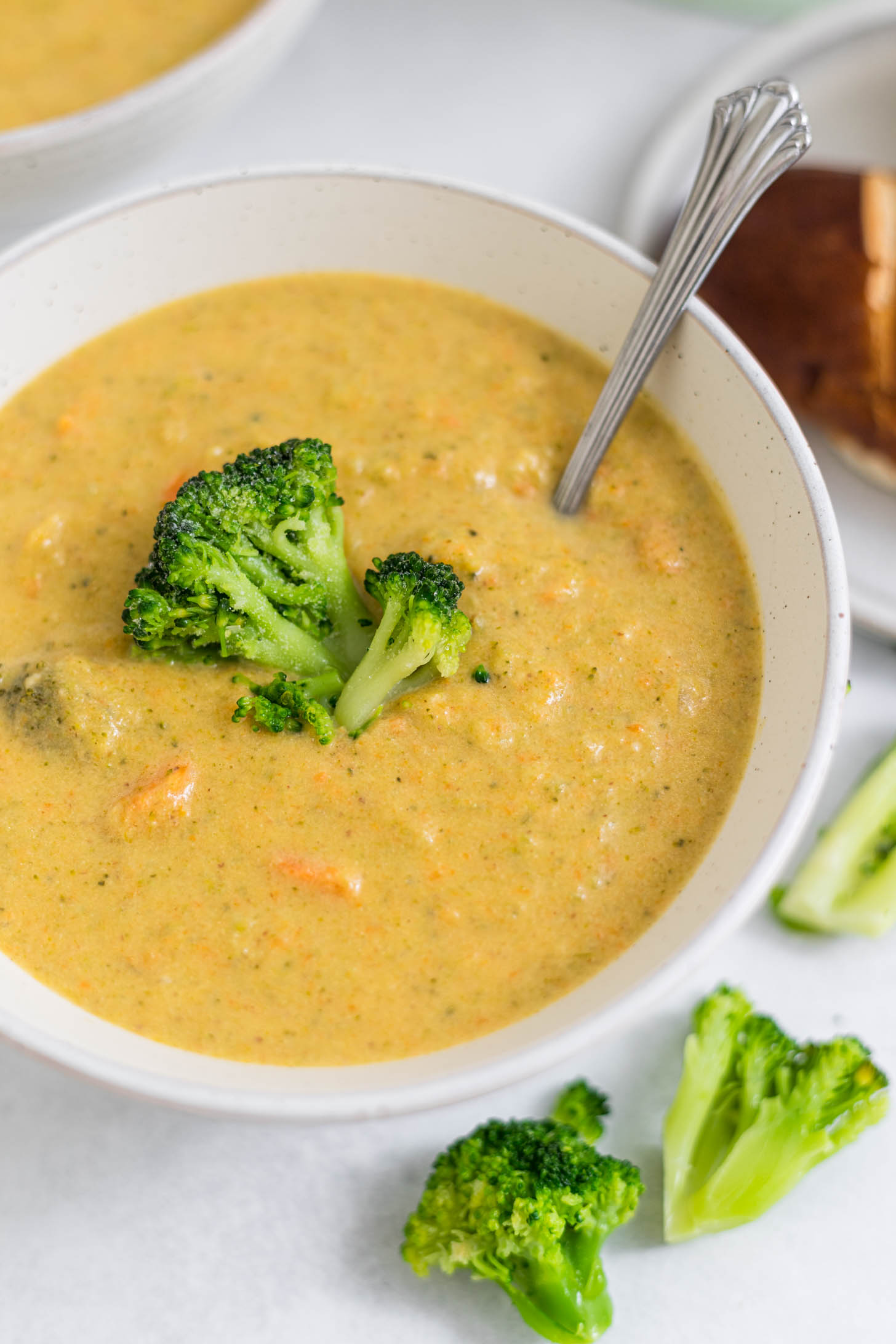 A bowl of gluten-free broccoli cheddar soup with a spoon in it.