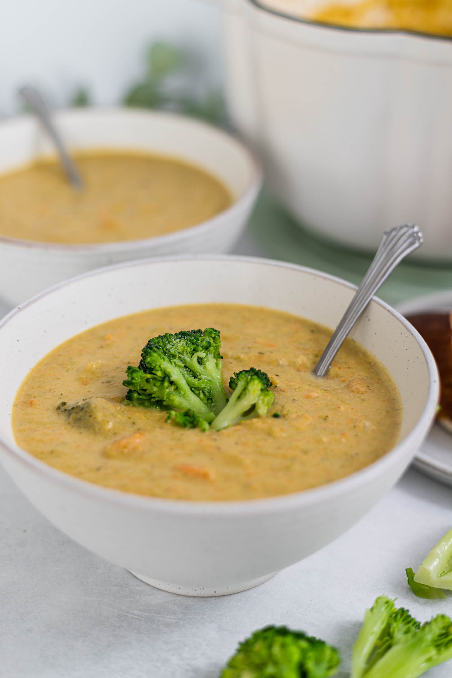 A side view of the soup in two serving bowls with broccoli florets resting on the soup.