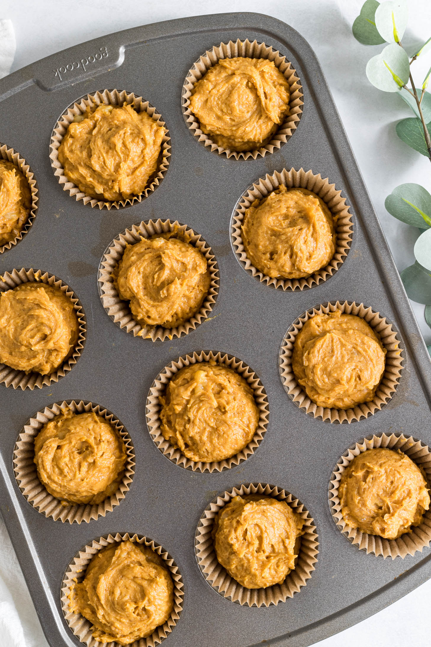 A muffin pan filled with pumpkin banana muffin batter.