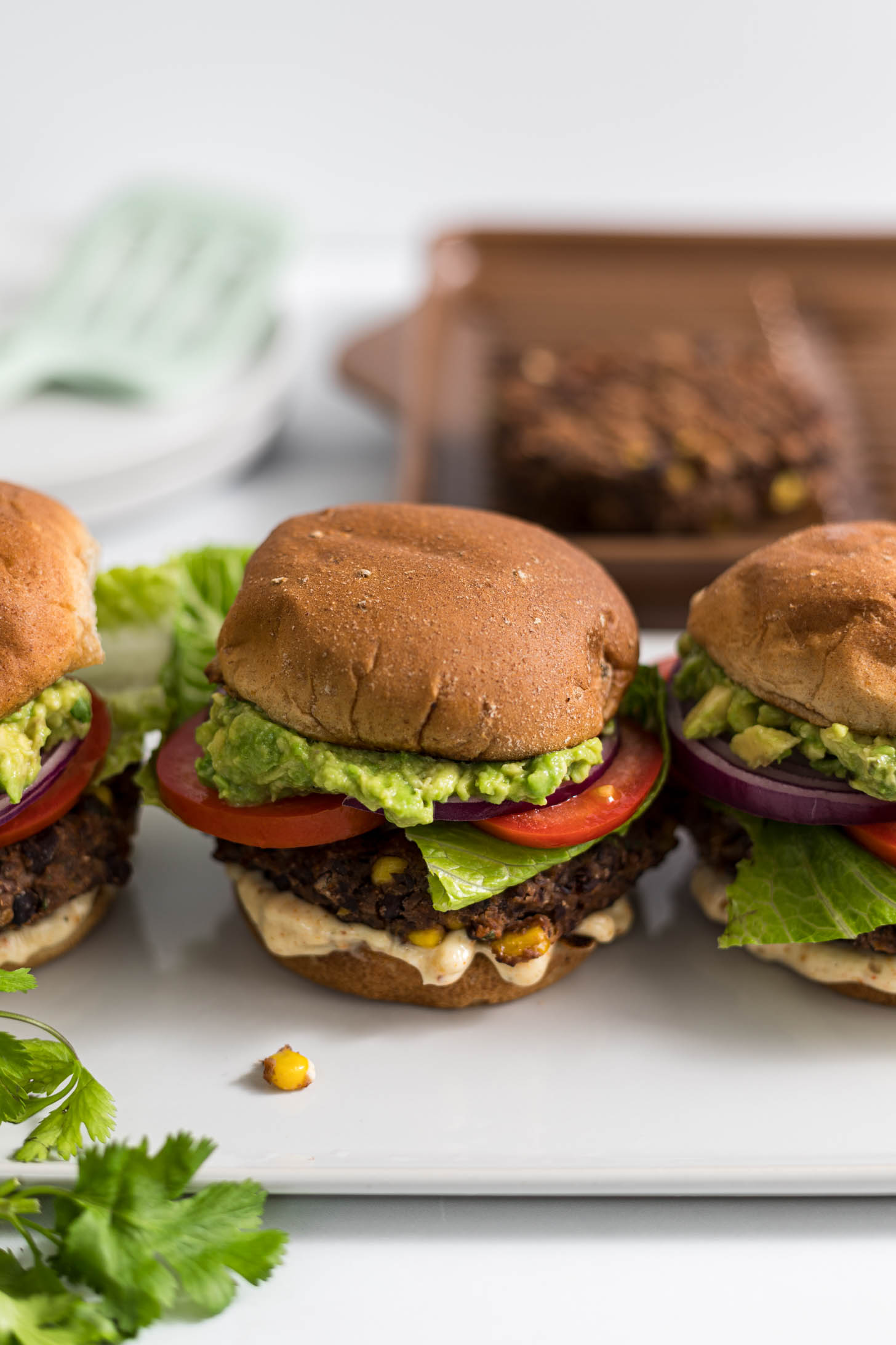 Three southwestern black bean burgers with a grill pan and spatula in the background.