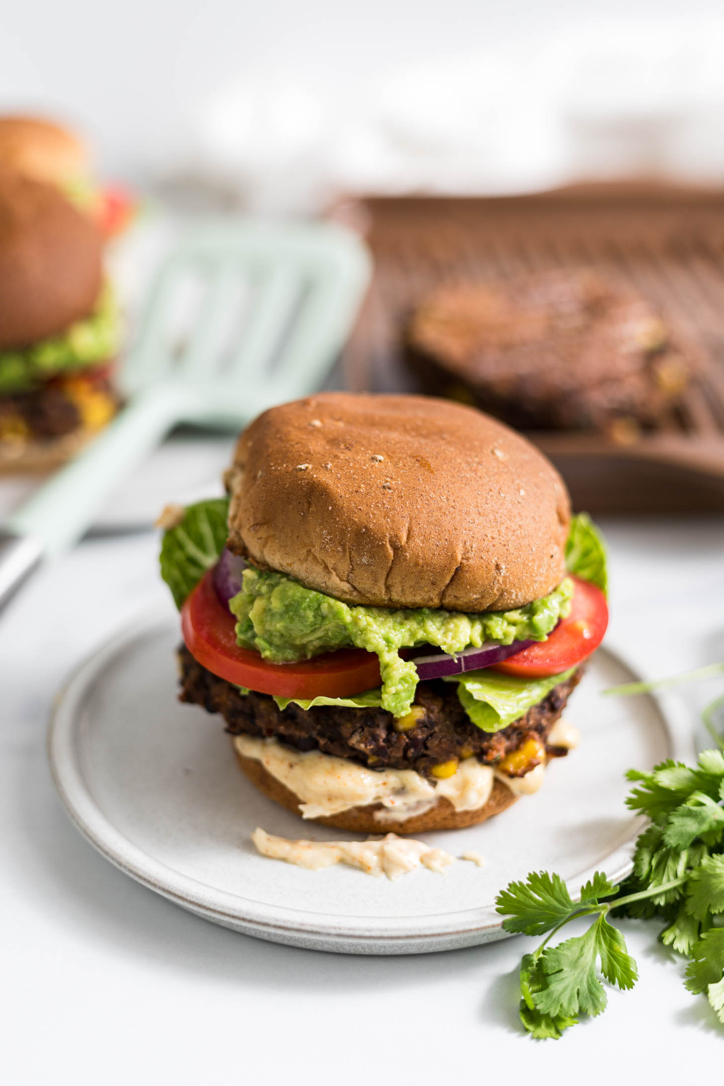 Southwest Black Bean Burger on a plate with a grill pan and spatula in the background.