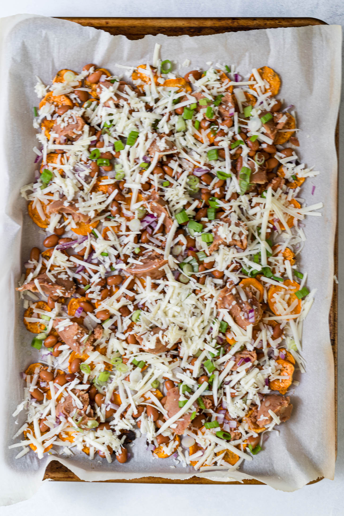 Nachos with toppings before they are baked.