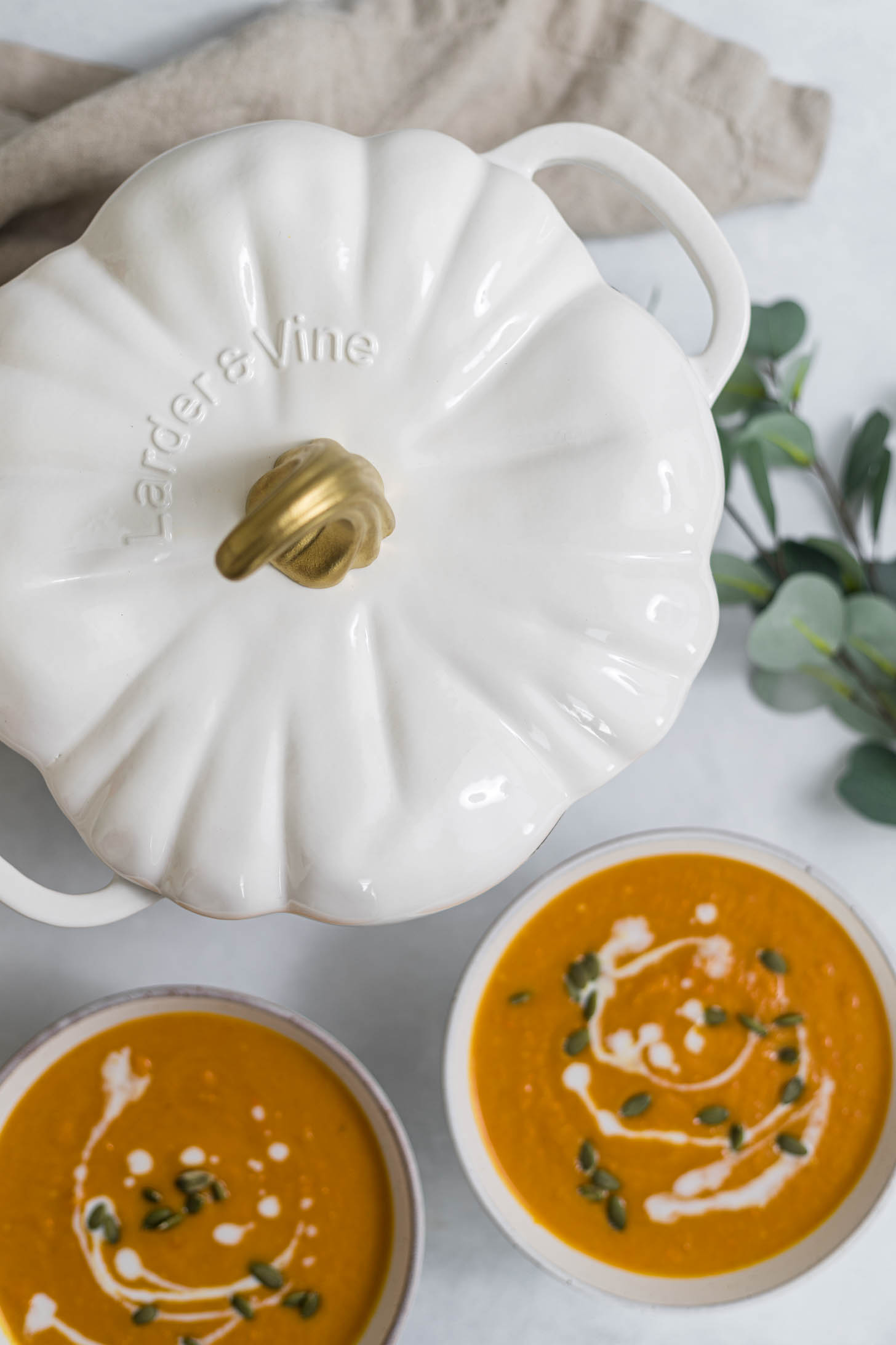 Overhead view of Pumpkin Dutch Oven and two bowls of carrot soup.