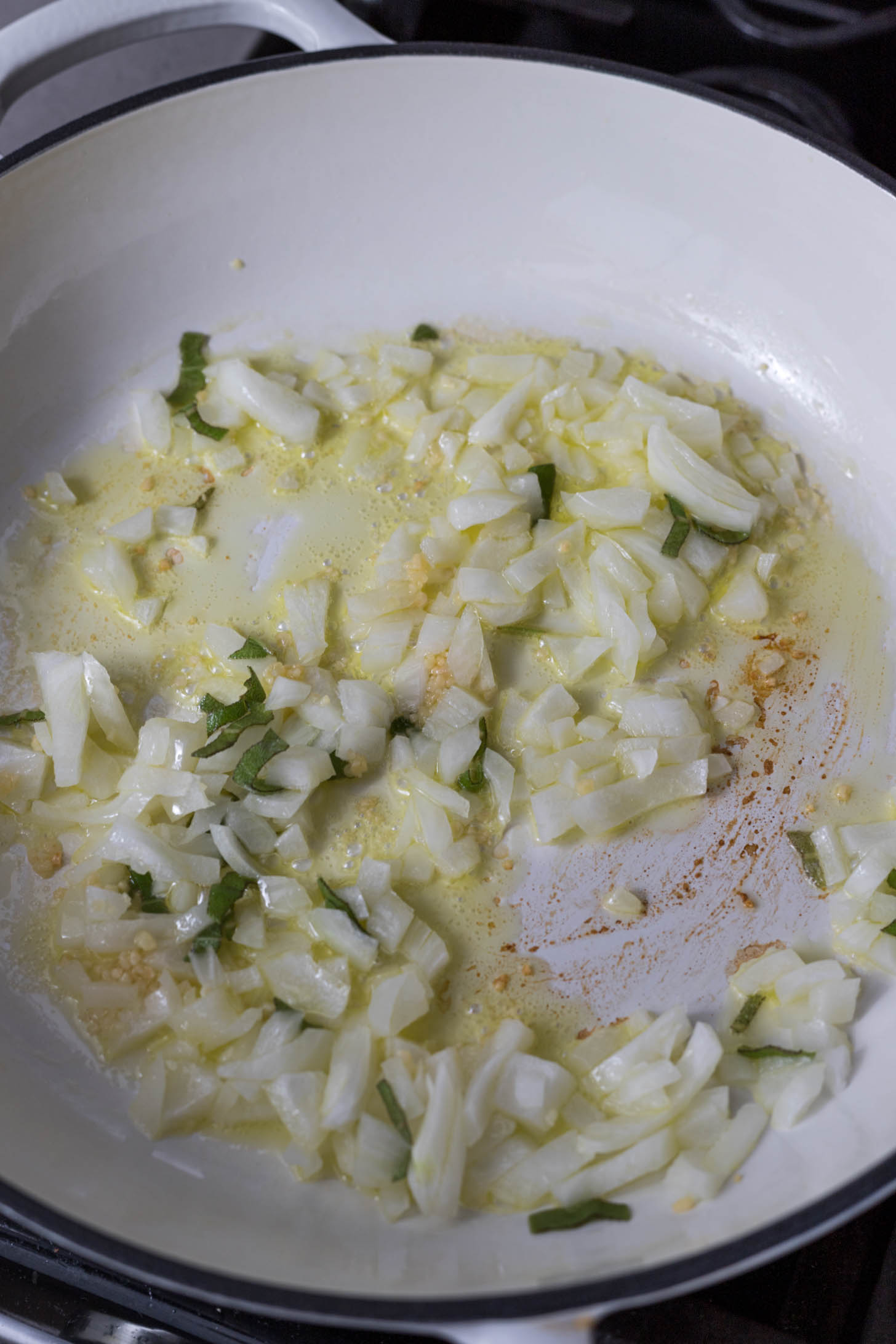 Onions and sage cooking in a braiser.