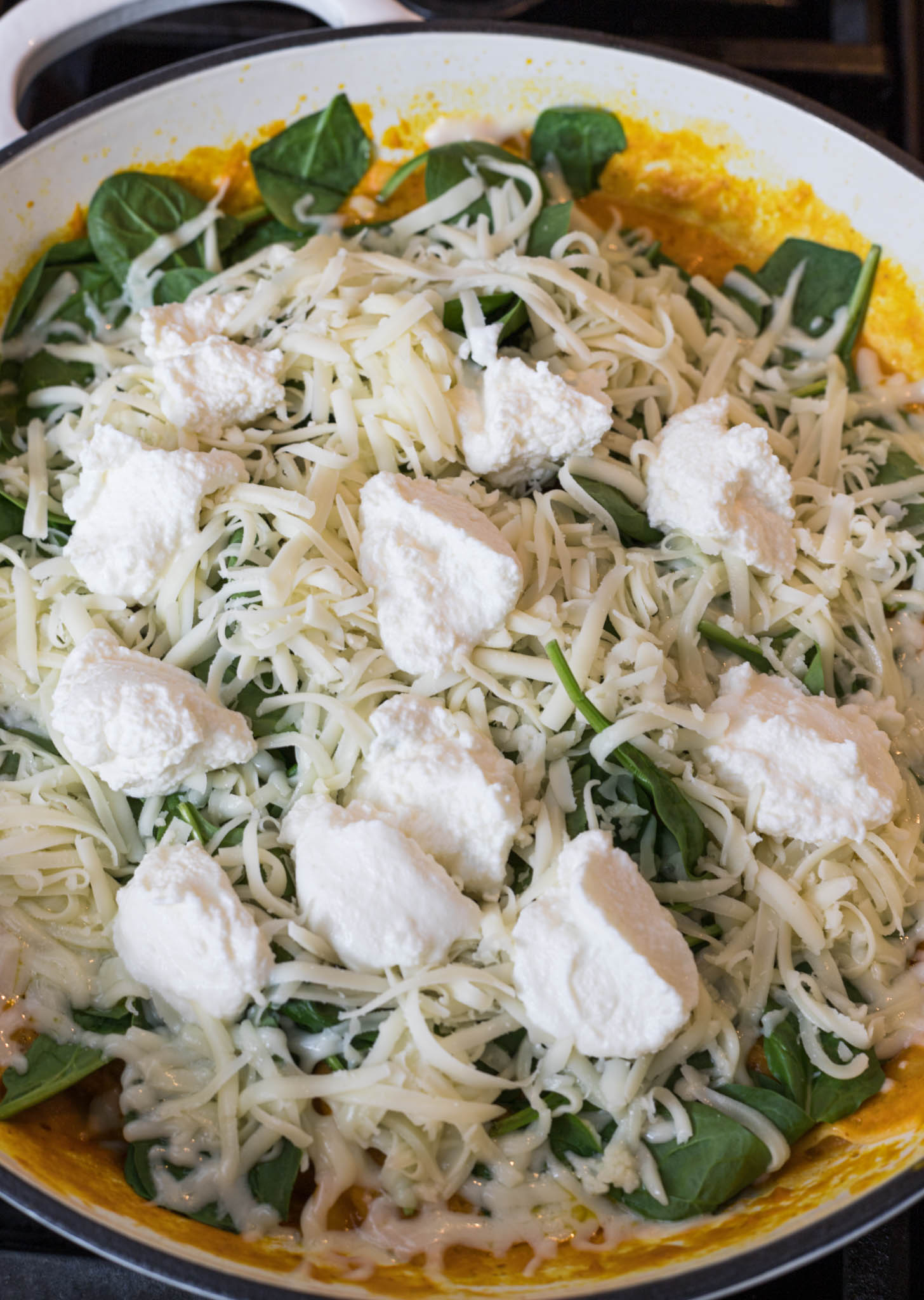 Lasagna topped with spinach, mozzarella, and ricotta cheese.